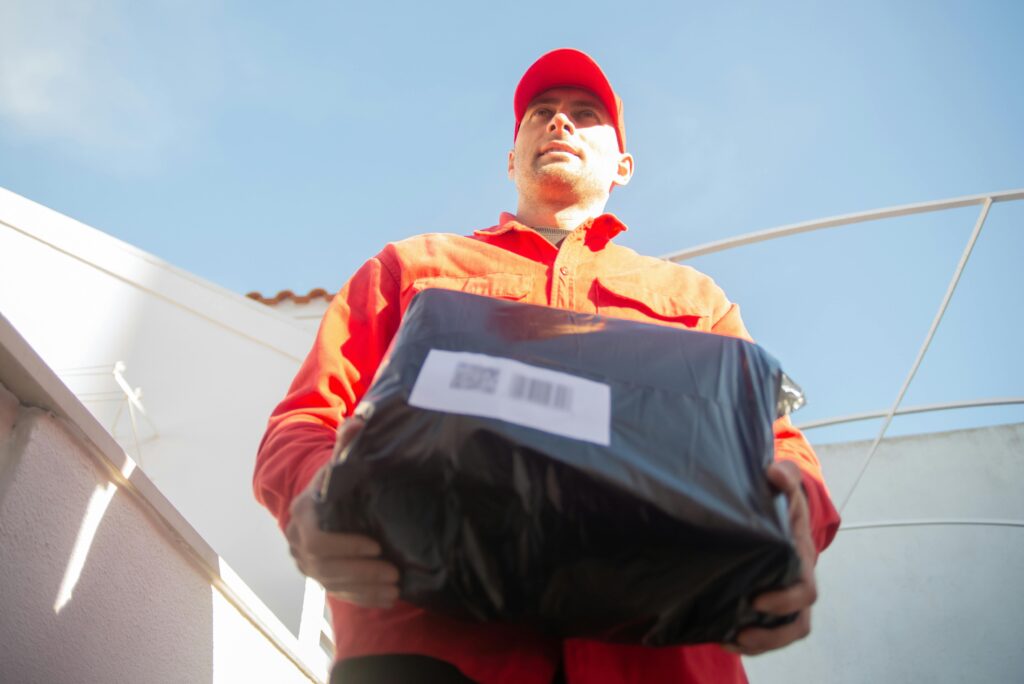 Low angle view of a courier in red uniform delivering a package outdoors in Portugal.
